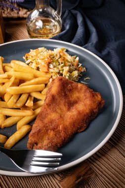 Kızarmış balık fileto, yanında patates kızartması ve salata..