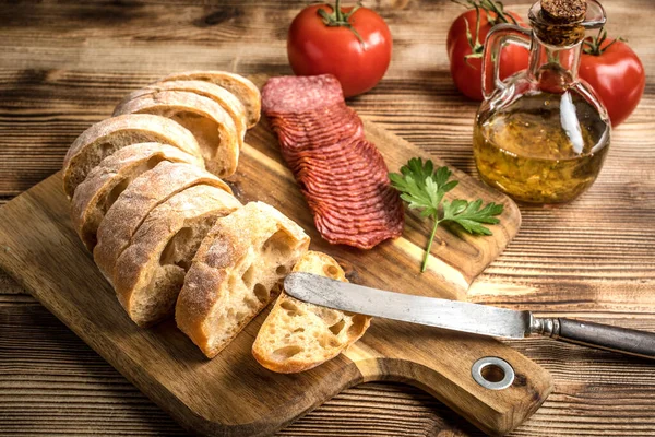 İtalyan ciabatta ekmeği Dilim salam ile Ahşap doğrama tahtası üzerinde kesilmiş.