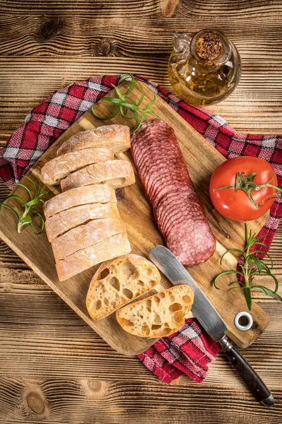İtalyan ciabatta ekmeği Dilim salam ile Ahşap doğrama tahtası üzerinde kesilmiş.