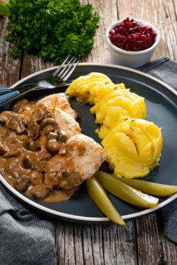 Mantar soslu ızgara tavuk göğsü, patates püresi ve salatalık turşusu ile servis edilir..