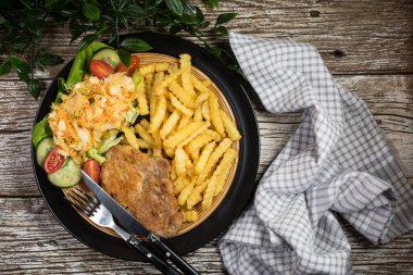 Geleneksel Polonya yemeği: kızarmış domuz pirzolası, patates kızartması ve salata ile servis edilir.. 