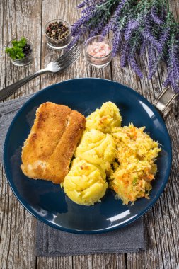 Haşlanmış patates ve sebze salatasıyla servis edilen kızarmış morina filetosu..