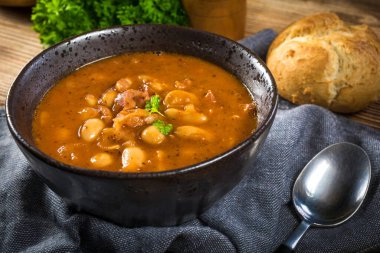 Domates soslu fasulye, pastırma ve siyah kasede sosis. Seçici odak.