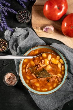 Domates soslu fasulye, pastırma ve siyah kasede sosis. Seçici odak.