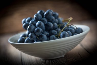 Kara üzüm kase ahşap masa üzerinde. Seçici odak.