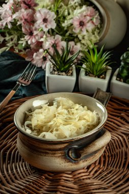 Hasır üzerinde bir kasede lahana turşusu.