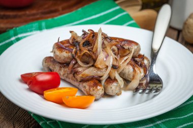 Kızarmış beyaz sosis tabakta soğan ile. Seçici odak.