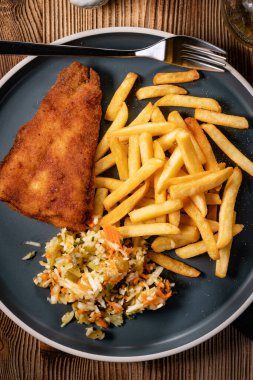 Kızarmış balık fileto, patates kızartması ve mavi tabakta salata. Üst görünüm.