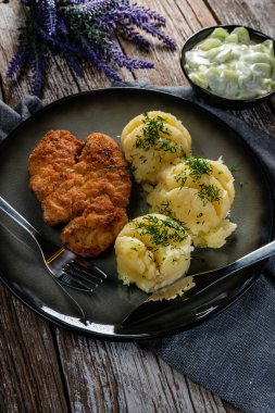 Domuz pirzolası, patates püresi ve salatalık salatasıyla servis edilir..