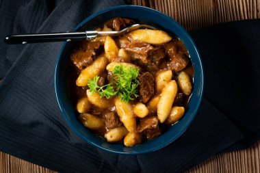 Soslu sığır eti yahnisi, patates köftesiyle servis edilir..