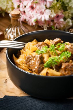 Tahta masada biftek soslu Tagliatelle yosunları. Koyu ışık.