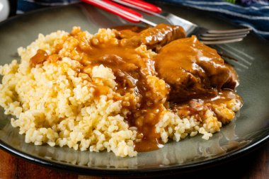 Kendi soslu haşlanmış domuz boyunlu arpa ve salatayla servis ediliyor. Sığ alan derinliği.