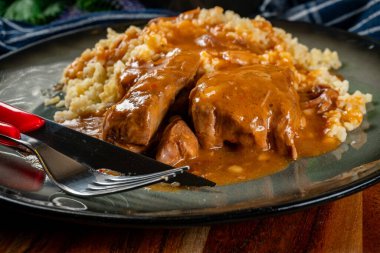 Kendi soslu haşlanmış domuz boyunlu arpa ve salatayla servis ediliyor. Sığ alan derinliği.