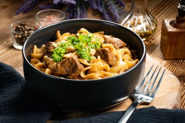 Tahta masada biftek soslu Tagliatelle yosunları. Koyu ışık.