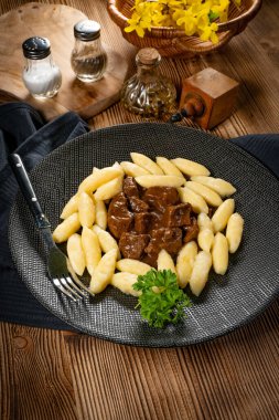 Soslu sığır eti yahnisi, patates köftesiyle servis edilir..