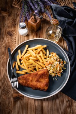 Kızarmış balık fileto, yanında patates kızartması ve salata..