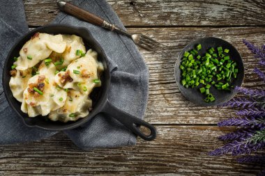 Fırında hamur köftesi (pierogi), içinde dökme demir tavada yeşillikler serpiştirilmiş..
