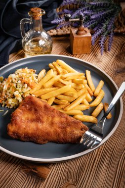 Kızarmış balık fileto, yanında patates kızartması ve salata..