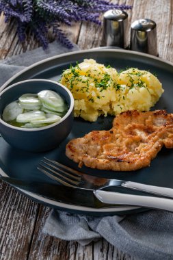 Domuz pirzolası, patates püresi ve salatalık salatasıyla servis edilir..