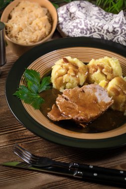Kendi sosunda haşlanmış patates ve kızarmış lahanayla servis edilen haşlanmış domuz boynu. Sığ alan derinliği.