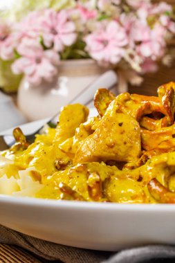Kremalı kızarmış tavuklu makarna ve ahşap masada chanterelle sosu..