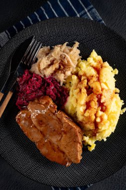 Patates püresi ve salata ile servis edilen soslu domuz budu..