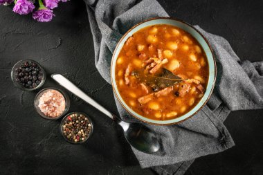 Domates soslu fasulye, pastırma ve siyah kasede sosis. Seçici odak.