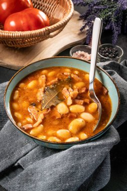 Domates soslu fasulye, pastırma ve siyah kasede sosis. Seçici odak.