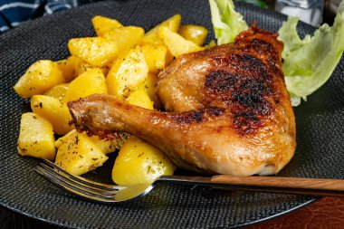 Appetizing baked chicken leg quarter with browned skin served with crispy fries for dinner.