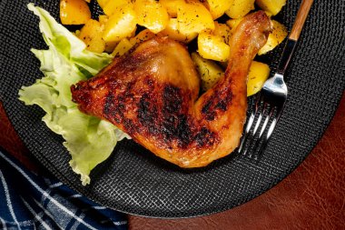Appetizing baked chicken leg quarter with browned skin served with crispy fries for dinner.