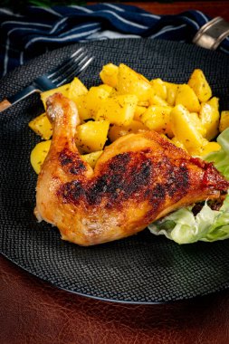 Appetizing baked chicken leg quarter with browned skin served with crispy fries for dinner.