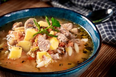 Beyaz sosis, patates ve küçük hamur köfteleriyle bezelye çorbası. Yüzeyin derinliği. Koyu ışık.