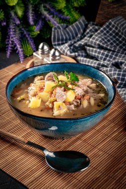 Beyaz sosis, patates ve küçük hamur köfteleriyle bezelye çorbası. Yüzeyin derinliği. Koyu ışık.