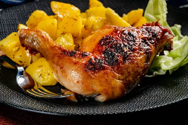 Appetizing baked chicken leg quarter with browned skin served with crispy fries for dinner.