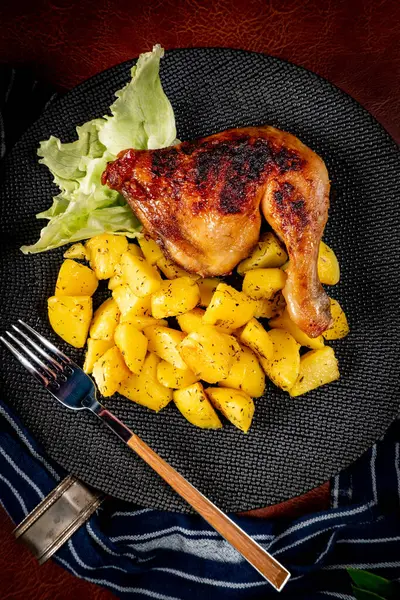 Appetizing baked chicken leg quarter with browned skin served with crispy fries for dinner.