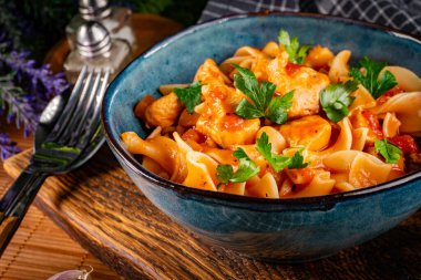 Domates soslu erişteli tavuk parçaları. Sığ alan derinliği.