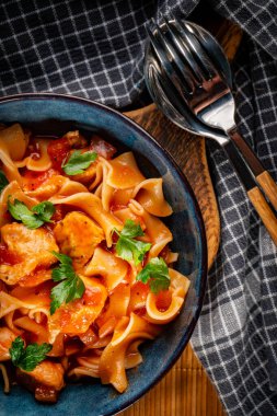 Domates soslu erişteli tavuk parçaları. Sığ alan derinliği.