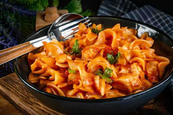 Domates soslu erişteli tavuk parçaları. Sığ alan derinliği.