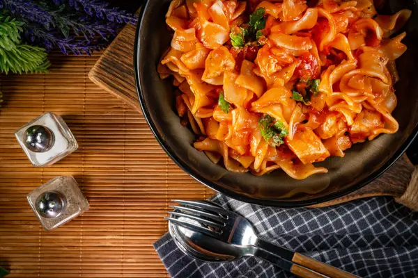 Domates soslu erişteli tavuk parçaları. Sığ alan derinliği.