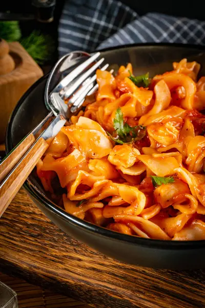 Domates soslu erişteli tavuk parçaları. Sığ alan derinliği.