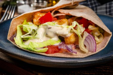 Kızarmış tavuk ve sebzeli salata. Baharatlı yaban turpu sosu ile sarılmış tortilla..