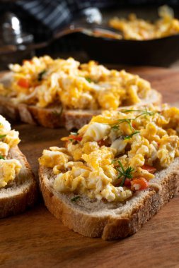 Bir dilim ekmeğin üzerinde çırpılmış yumurta, kırmızı biber, bitki ve domatesle kızartılmış..