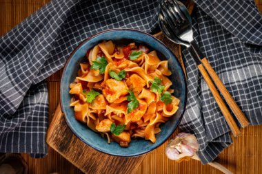 Domates soslu erişteli tavuk parçaları. Sığ alan derinliği.