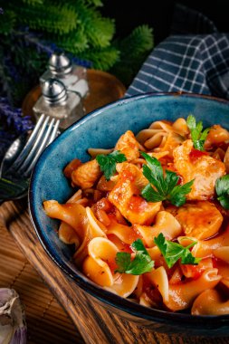 Domates soslu erişteli tavuk parçaları. Sığ alan derinliği.