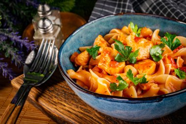 Domates soslu erişteli tavuk parçaları. Sığ alan derinliği.