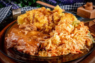 Patates püresi ve salatayla servis edilen acılı soslu domuz pirzolası. Sığ alan derinliği.