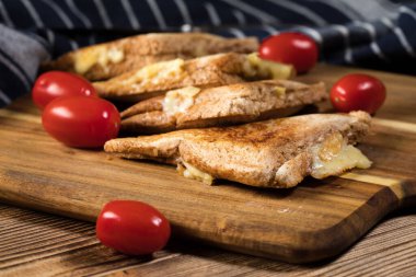 Kızarmış peynirli sandviçi doğrama tahtasında. Sığ alan derinliği.