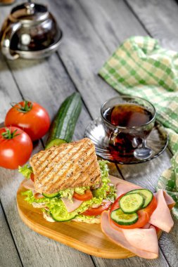 Sandviç ile jambon, salatalık, domates, marul, dolum üç dilim kızarmış ekmek arasında iki kat ile.