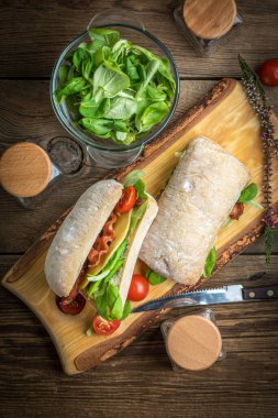 Ciabatta ahşap tahta üzerinde Roka Salatası, pastırma ve sarı peynirli sandviç. Üstten Görünüm.