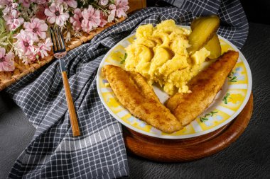 Kızarmış ekmek parçaları patates püresi ve salatalık turşusuyla servis ediliyor..